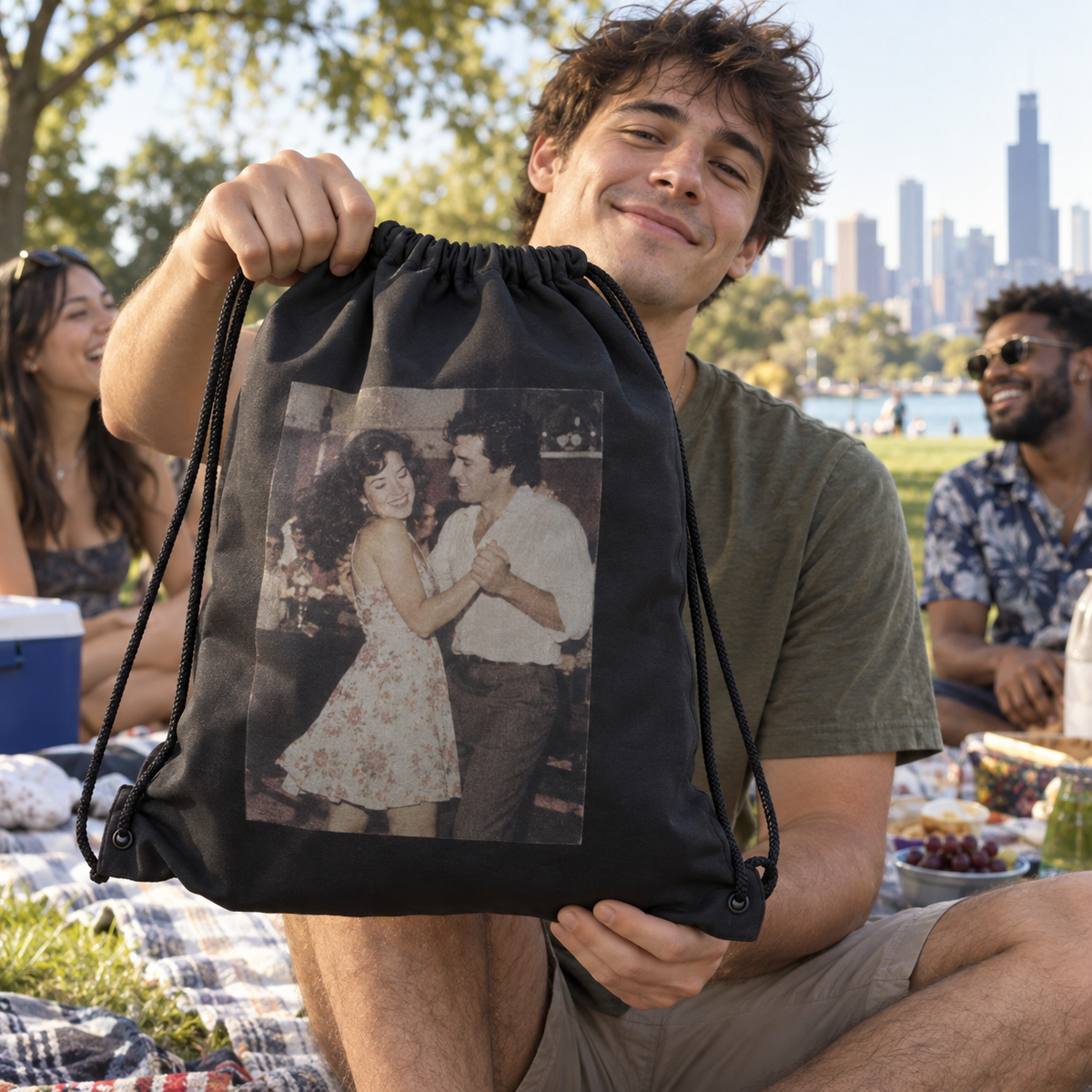 A drawstring bag printed with an old photo of parents dancing, held at a picnic.