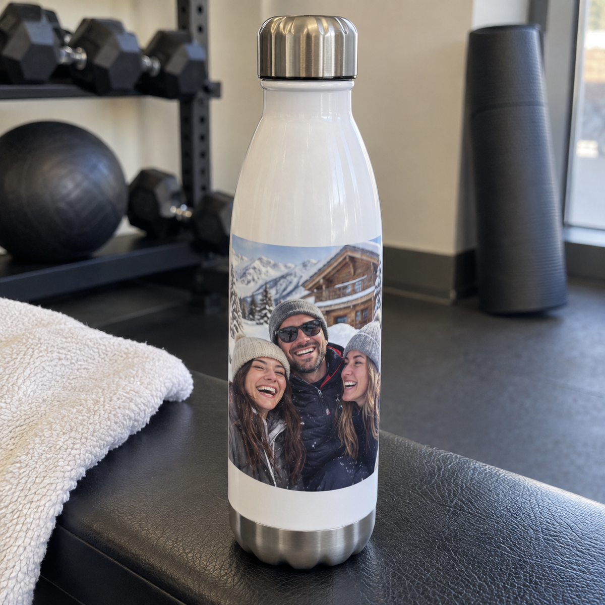 An insulated white water bottle printed with a past snowy chalet photo of friends in a gym.
