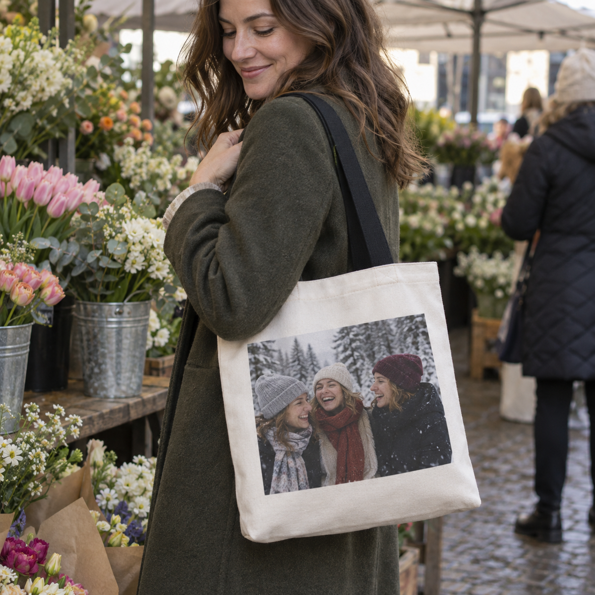 A canvas tote bag printed with a winter friends' photo, carried at a flower market.