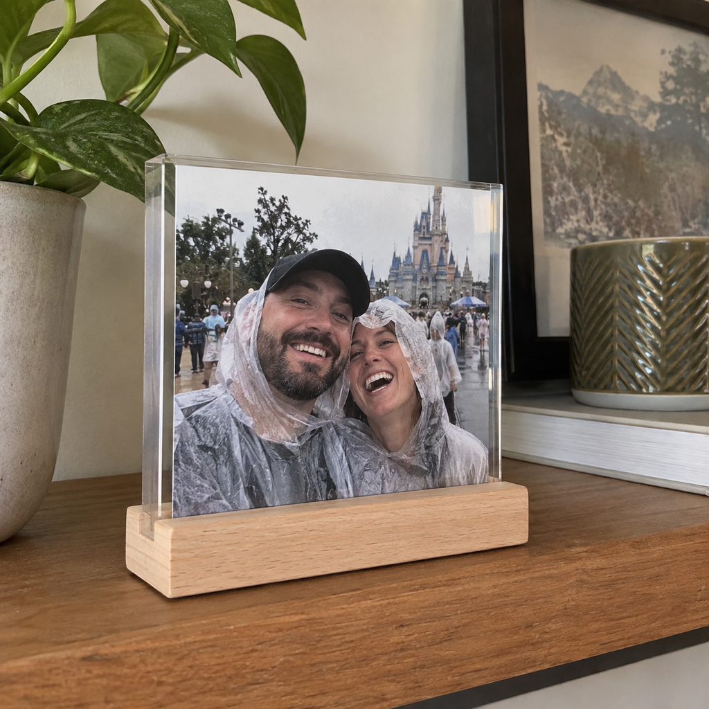 An acrylic photo sign with a wooden stand showing a couple on a rainy outing.