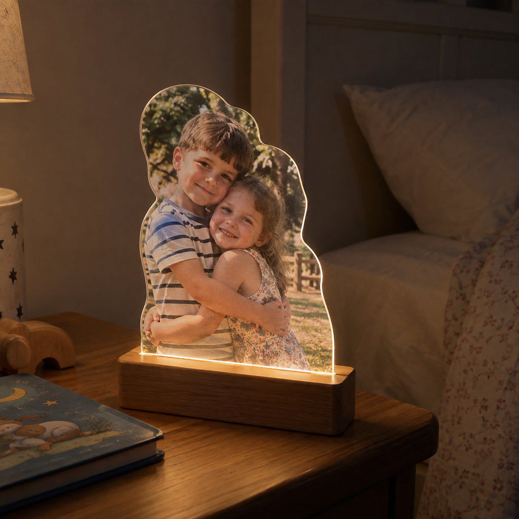 Custom-shaped acrylic night light printed with a sunny sibling photo on a dim child's bedside table.