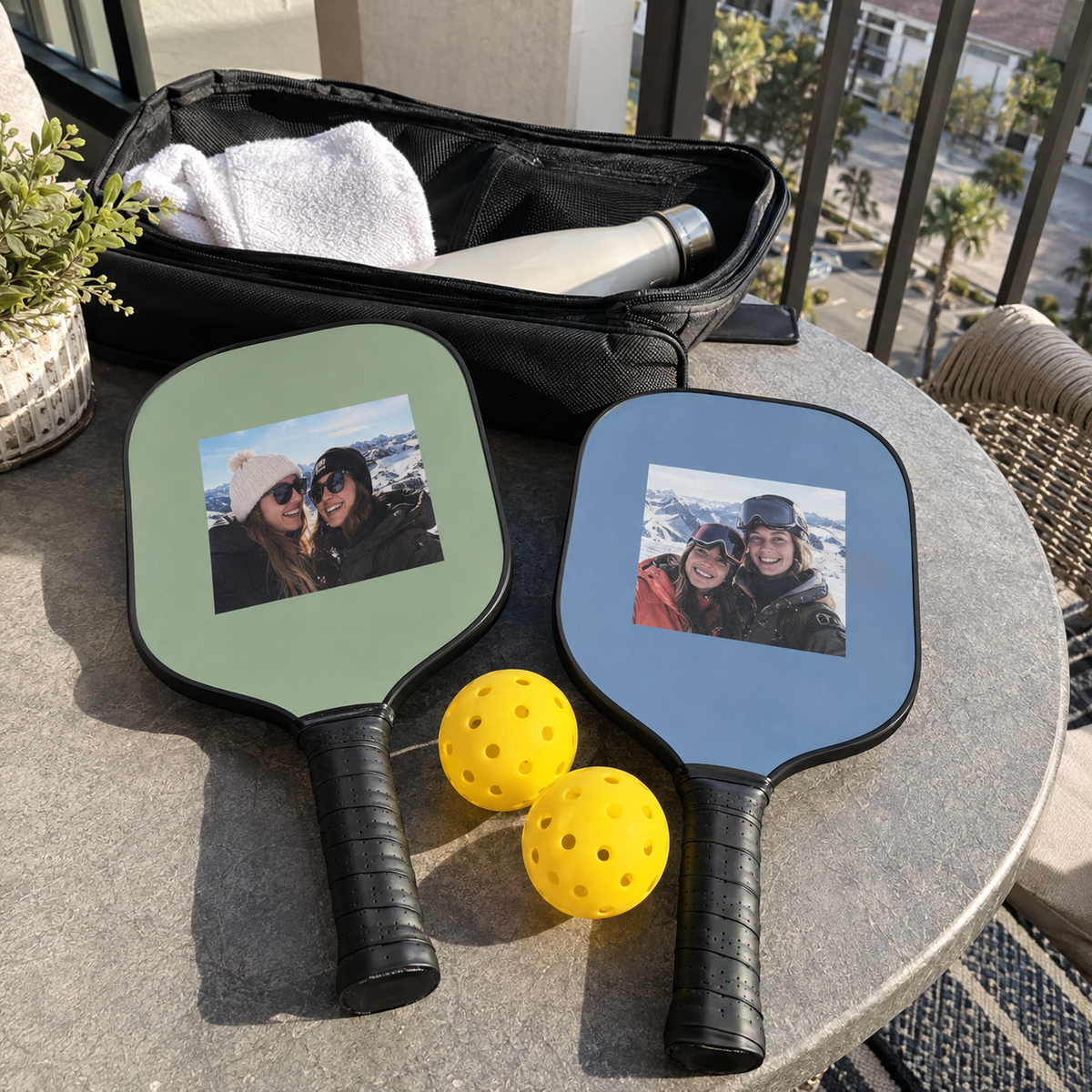 Two personalized pickleball paddles with old ski trip photos, shown with balls and their carrying case.